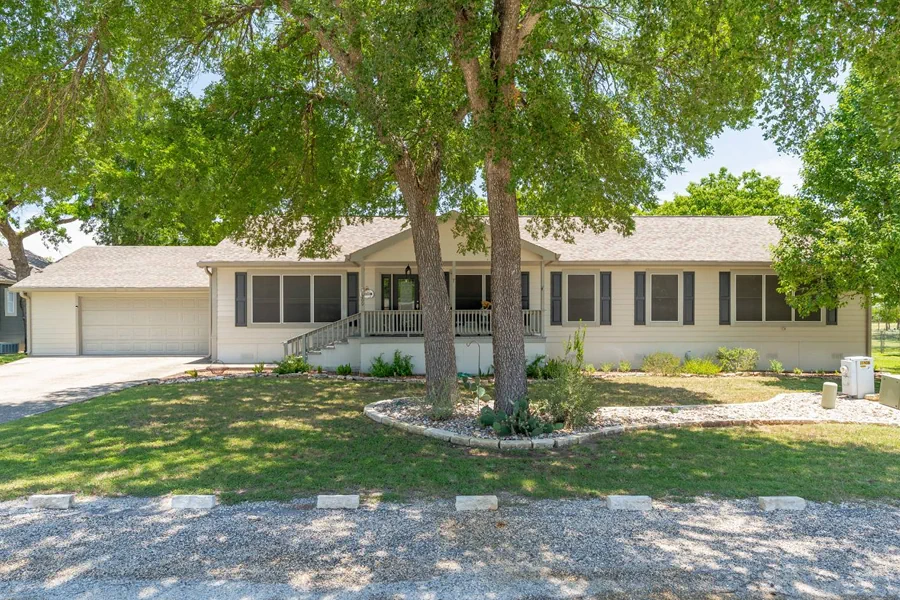 Spacious living room in a retirement home with comfortable seating and large windows providing a view of green hill country landscape bathed in sunlight creating a peaceful and welcoming atmosphere